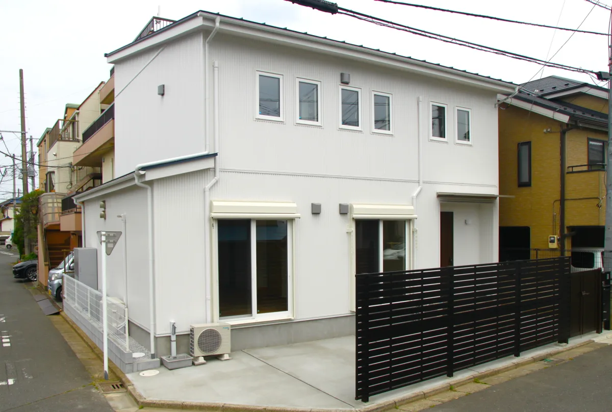 白い外壁と黒いフェンスのある二階建て住宅の外観